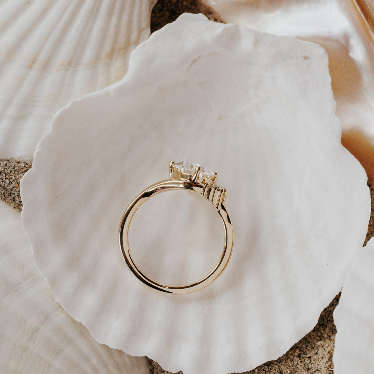 The Horizon Oval Ring in 14k yellow gold featuring a lab-grown oval diamond center stone with a round tapered diamond half halo, shown from above on a white shell to display the band profile.