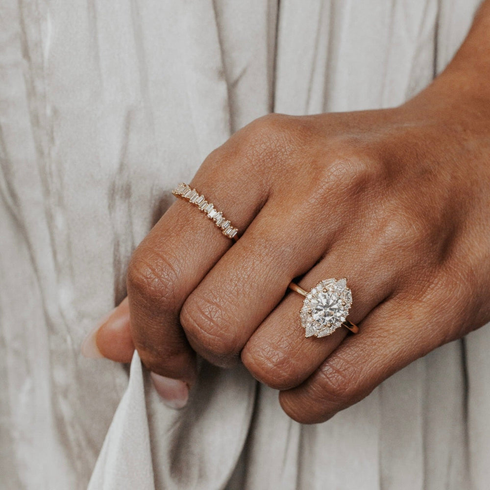 The Lori Round Ring in 14k yellow gold worn on the ring finger, styled with a baguette diamond band on the middle finger.

