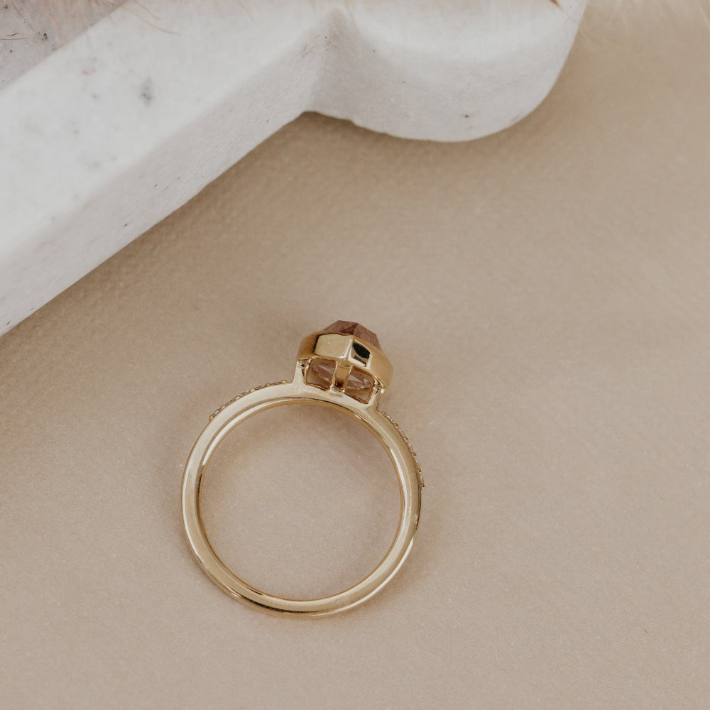 The Lyell 3.24 ct Pear Clear and Peach Rustic Diamond Ring in 14k yellow gold featuring a pear-shaped rose cut rustic diamond in a milgrain bezel with pave diamond band, shown from above to display the open setting structure and pave band.