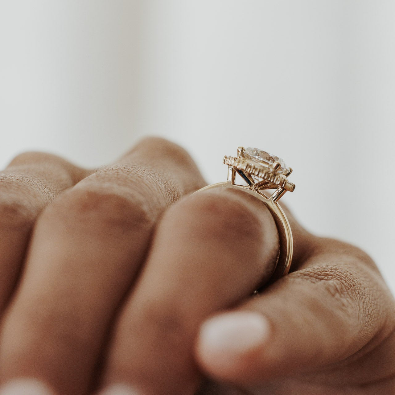The North Star Ring in 14k yellow gold worn on the ring finger, shown from a side profile angle highlighting the baguette diamond halo setting against a white background.