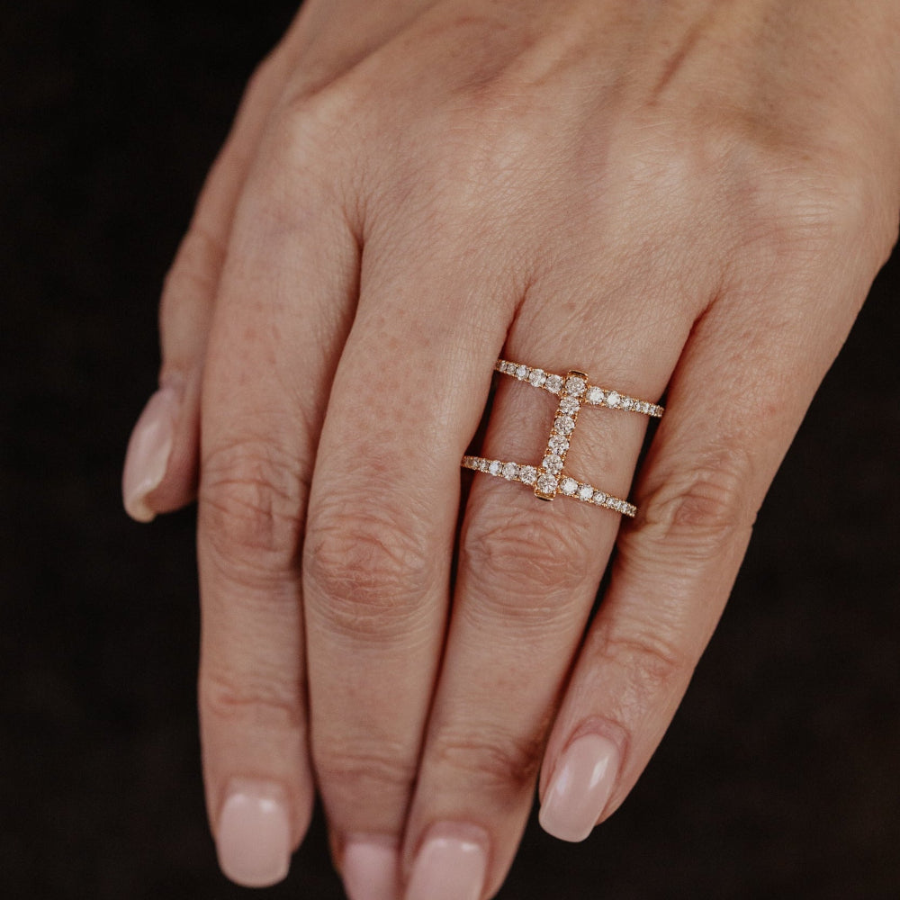 Hand wearing a diamond wedding band on a dark background.