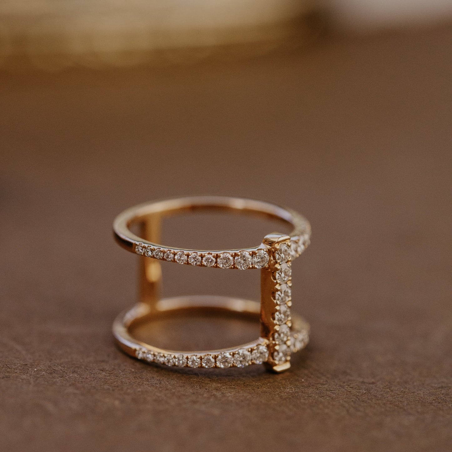 Rose gold wedding band with diamond accents on a brown surface.