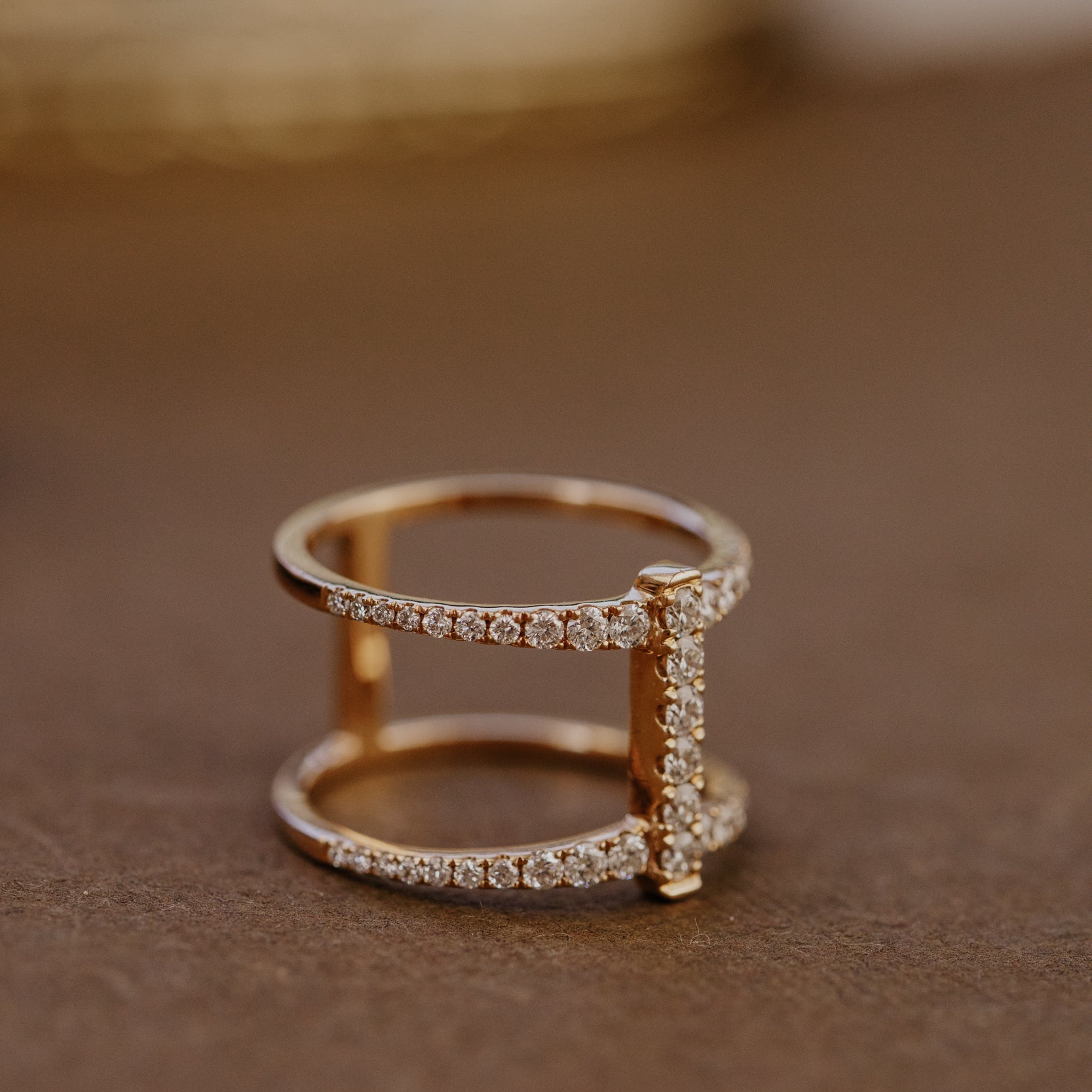 Rose gold wedding band with diamond accents on a brown surface.