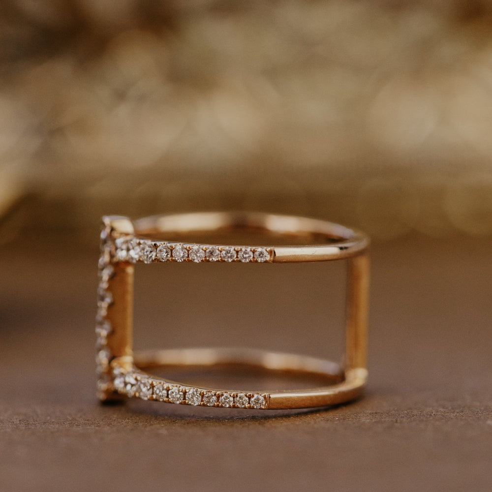 Rose gold wedding band with diamond accents on a brown background.