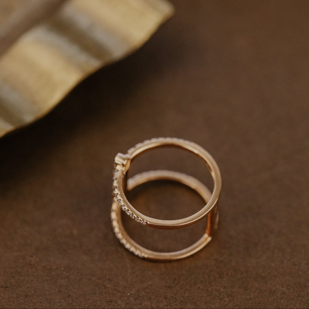 Rose gold wedding band with diamond accents on a brown surface.