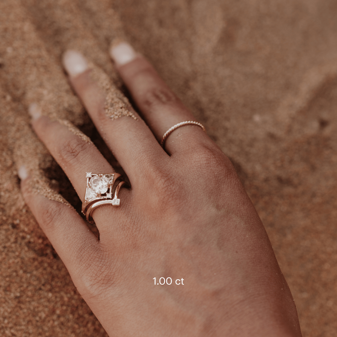 The Tulum Oval Ring in 14k yellow gold featuring a lab-grown oval diamond center stone with trillion and princess cut diamond accents in a geometric halo, worn on the ring finger alongside a contoured matching band and gold stacking ring.
