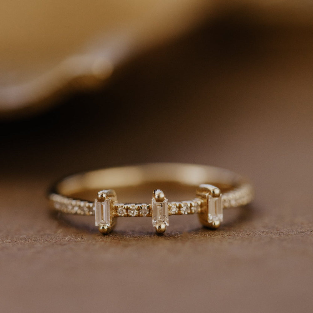 Gold wedding bands with small diamonds and pave diamond band on a brown surface.