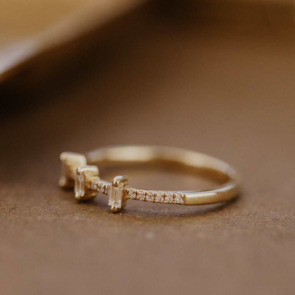 Gold wedding band with diamonds on a brown surface