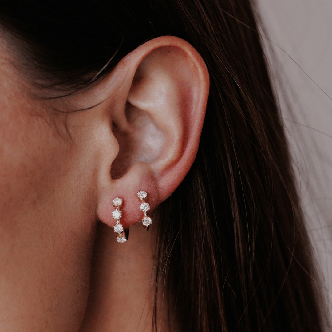 14k gold three prong set lab grown hoop earrings showcased on the ear of a model. 