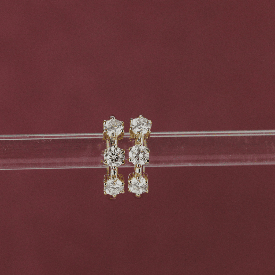 14k gold three prong set lab grown hoop earrings showcased on a clear tube in the center of the frame. 