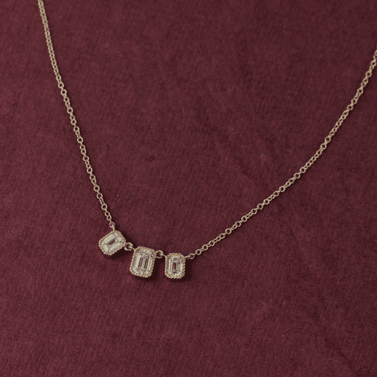 14k gold emerald cut, 3 milgrain, lab grown diamond chain bracelet showcased on a textured red surface.