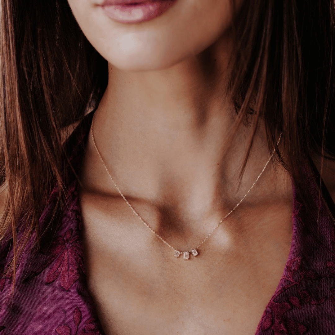 14k gold emerald cut, 3 milgrain, lab grown diamond chain bracelet showcased on the neck of a model.