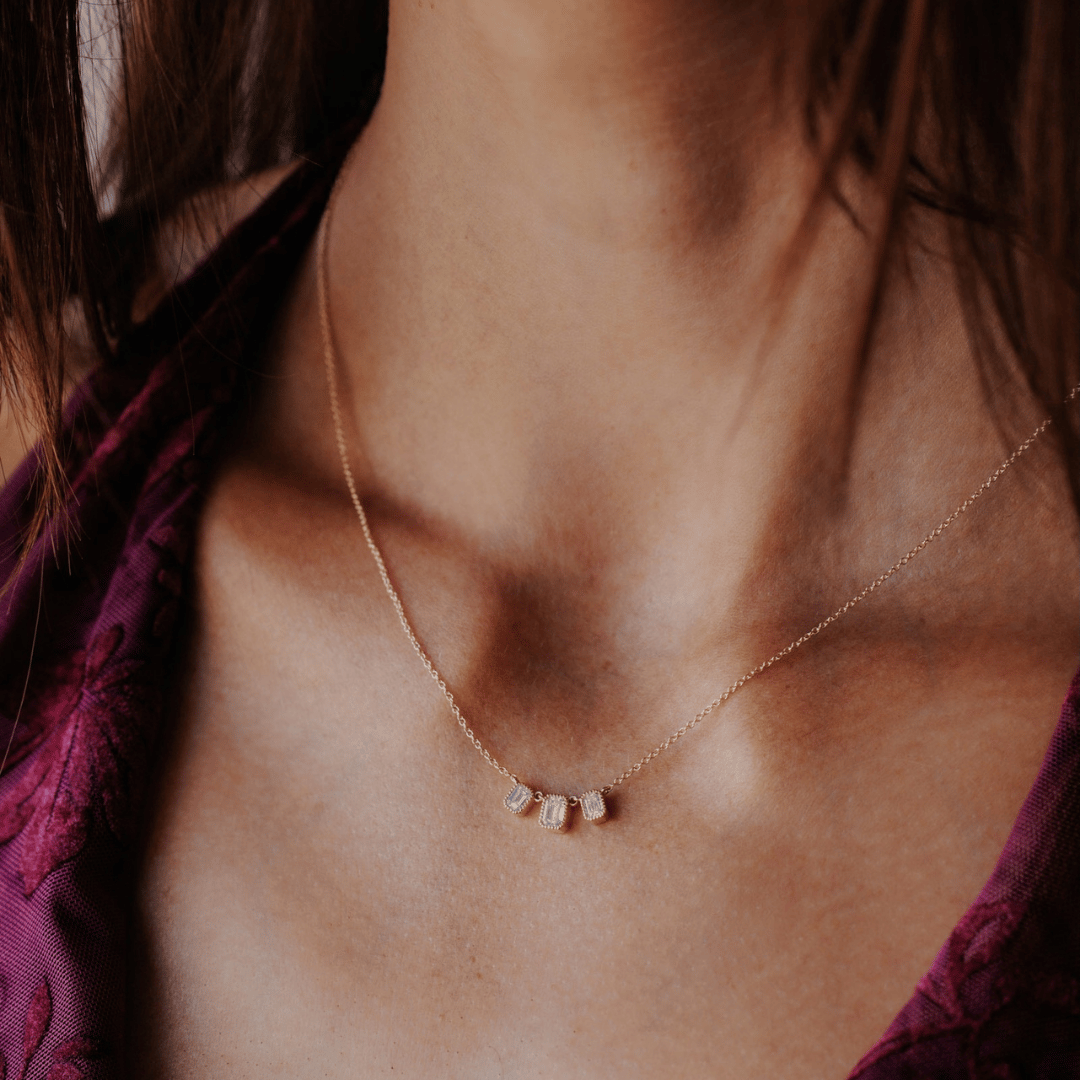 14k gold emerald cut, 3 milgrain, lab grown diamond chain bracelet showcased on the neck of a model.