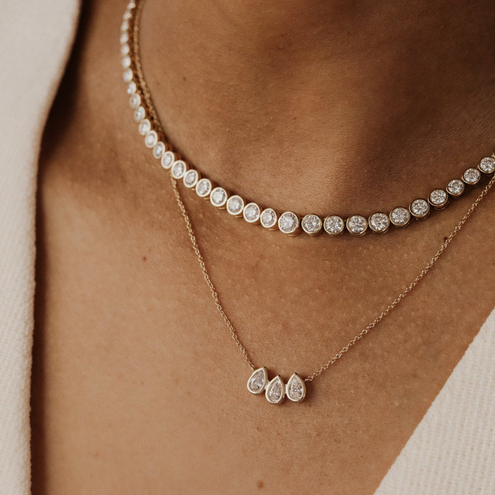 Close-up of a person wearing two gold diamond necklaces.