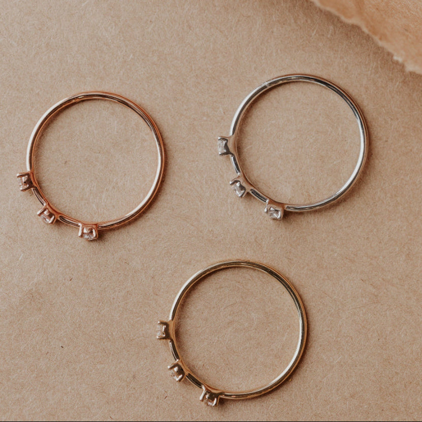 Three wedding bands on a beige paper background.