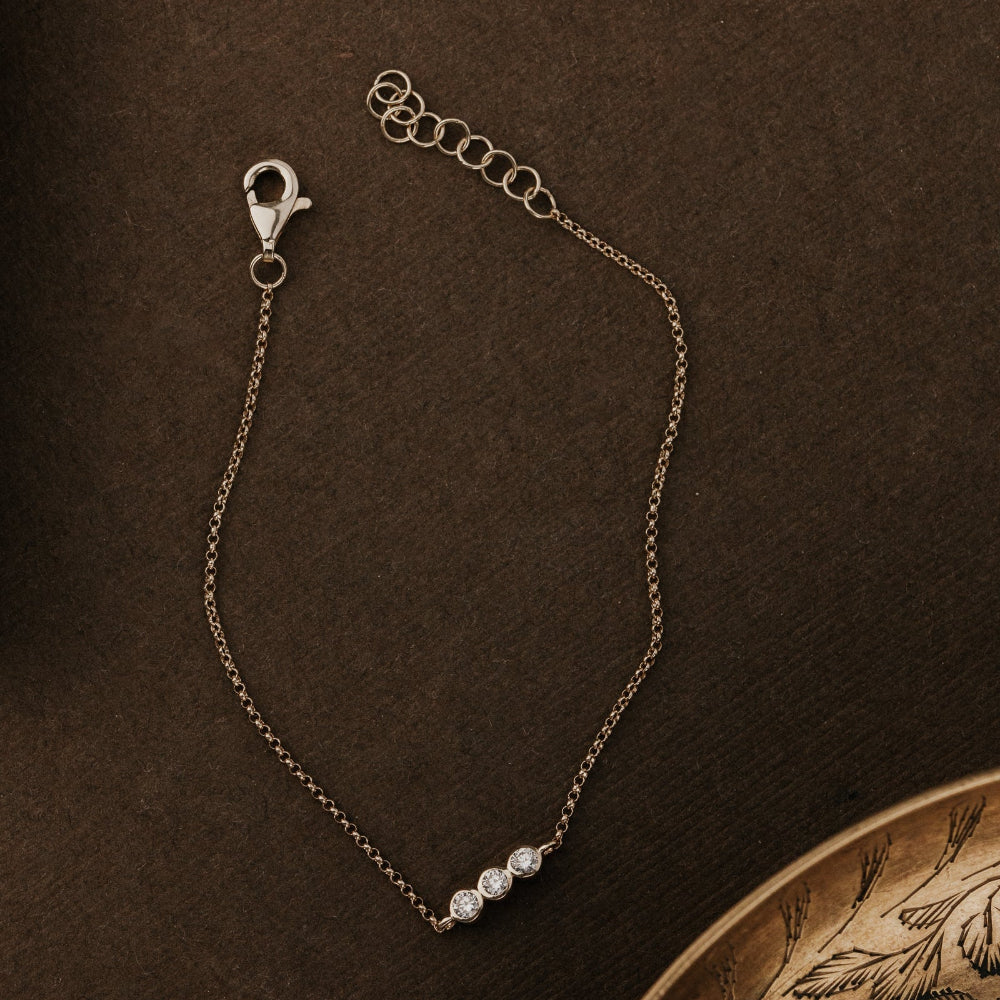 Gold bracelet with a clasp on a brown textured background.