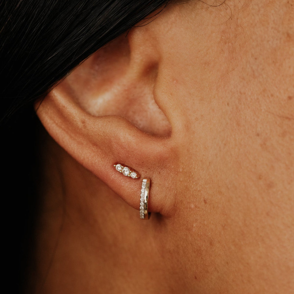 Close-up of an ear wearing a diamond earring and hoop.