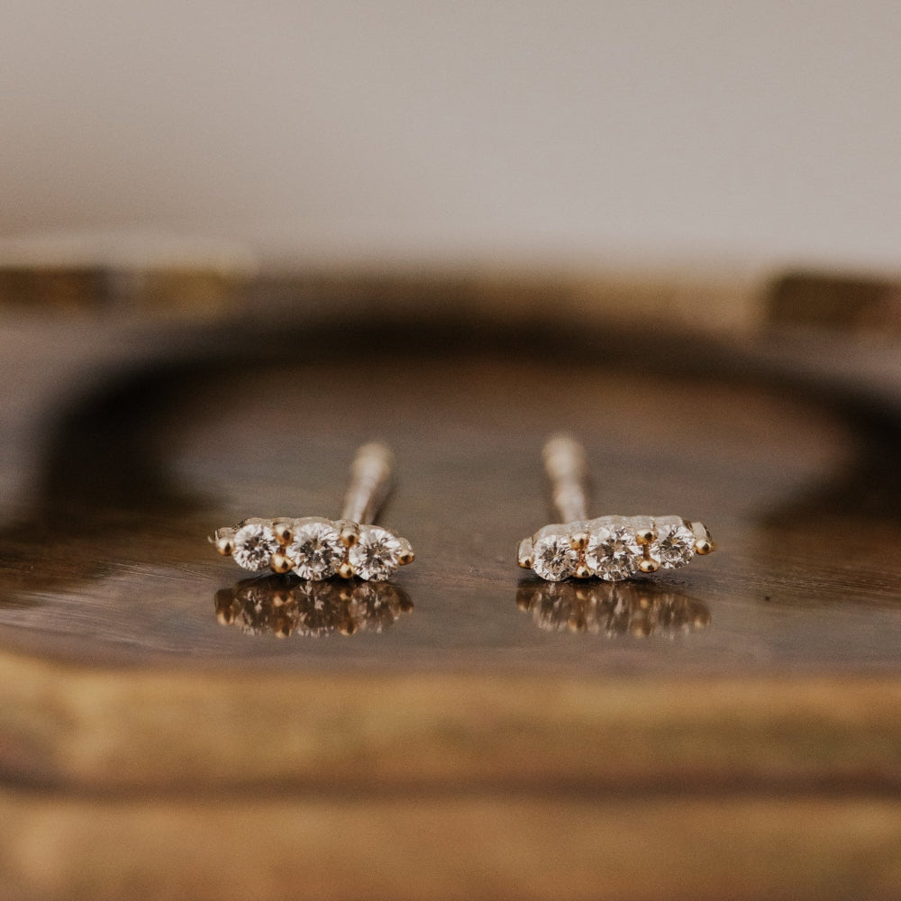 Pair of diamond stud earrings on a wooden surface.