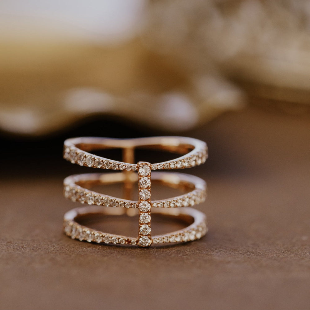 Rose gold wedding with three pave diamond bands on a textured surface.