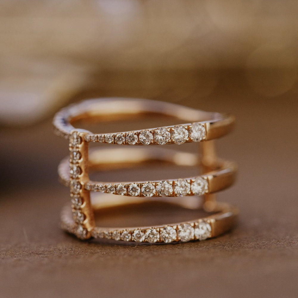 Rose gold wedding band with diamond accents on a brown surface.