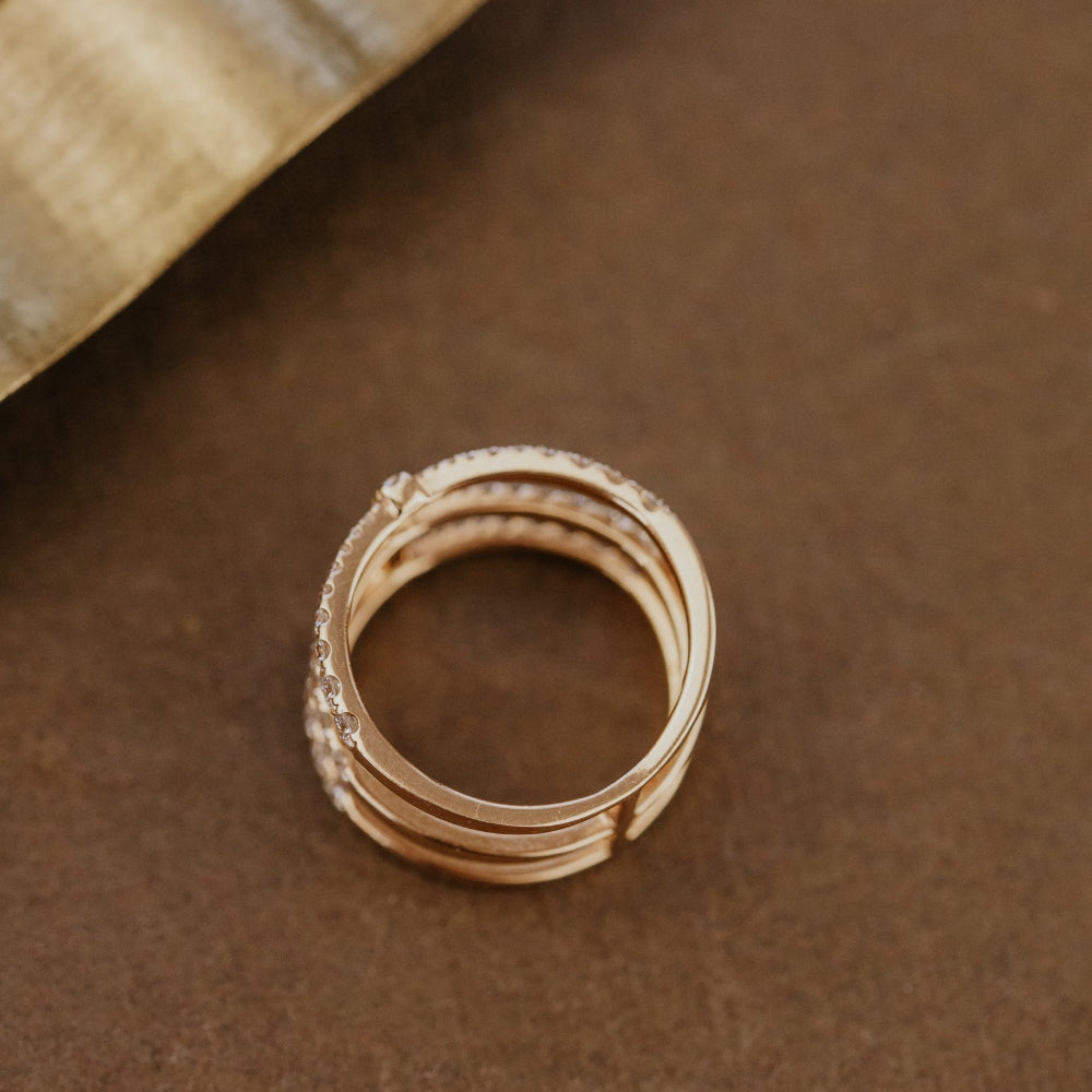Rose gold wedding band ring on a brown surface with a textured background.