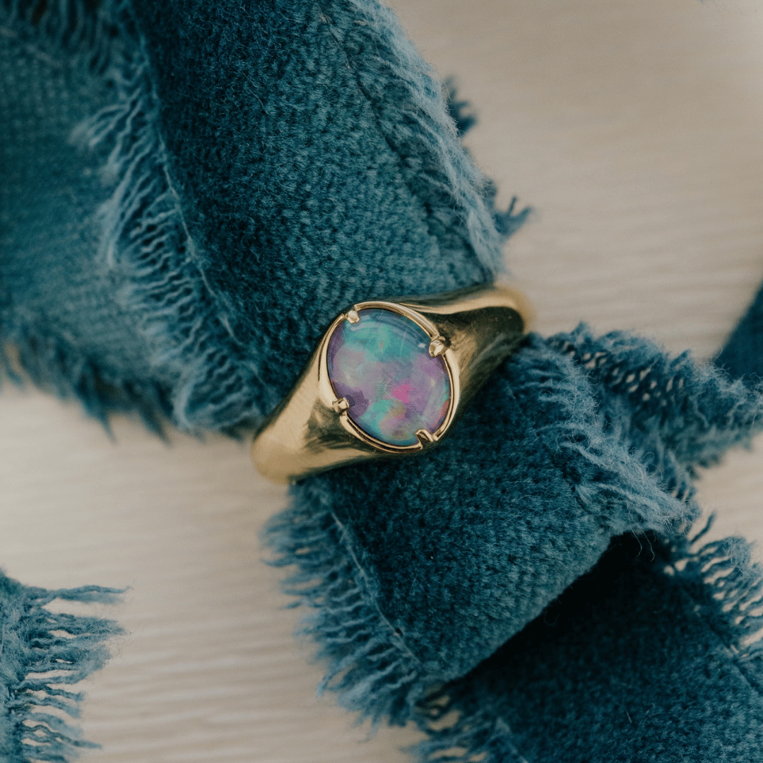 Opal Triplet Signet ring on green fabric.