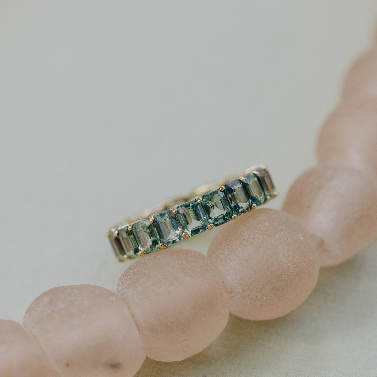 Amara band with green sapphires on a pink beaded necklace.