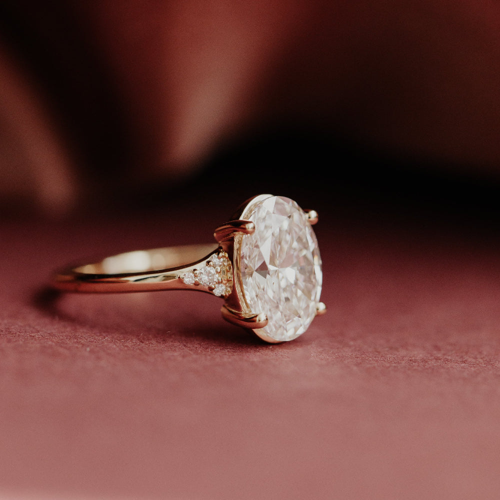 Yellow Angie gold engagement ring with a large oval diamond on a red fabric background.