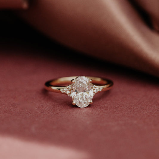 Close up of the Angie oval diamond engagement ring on a red surface.