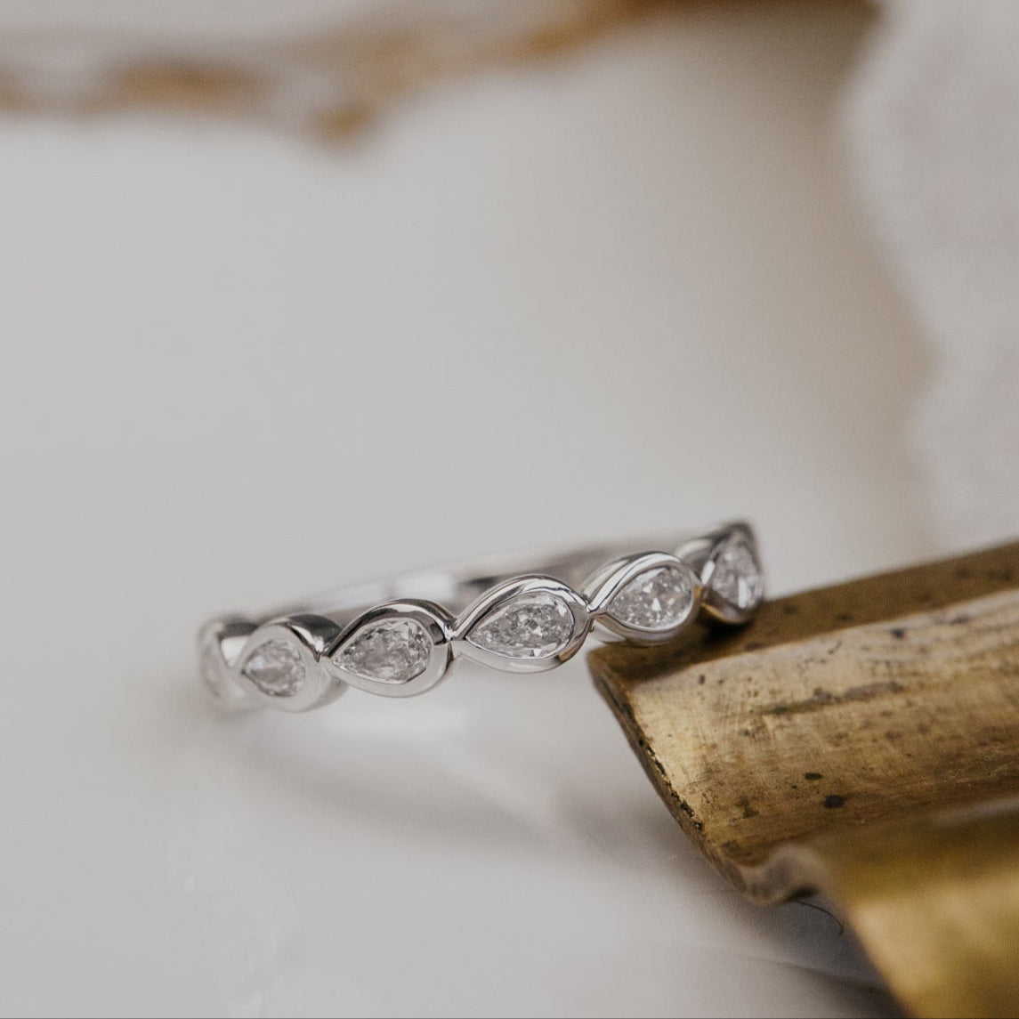 White gold wedding band with diamonds on a textured surface