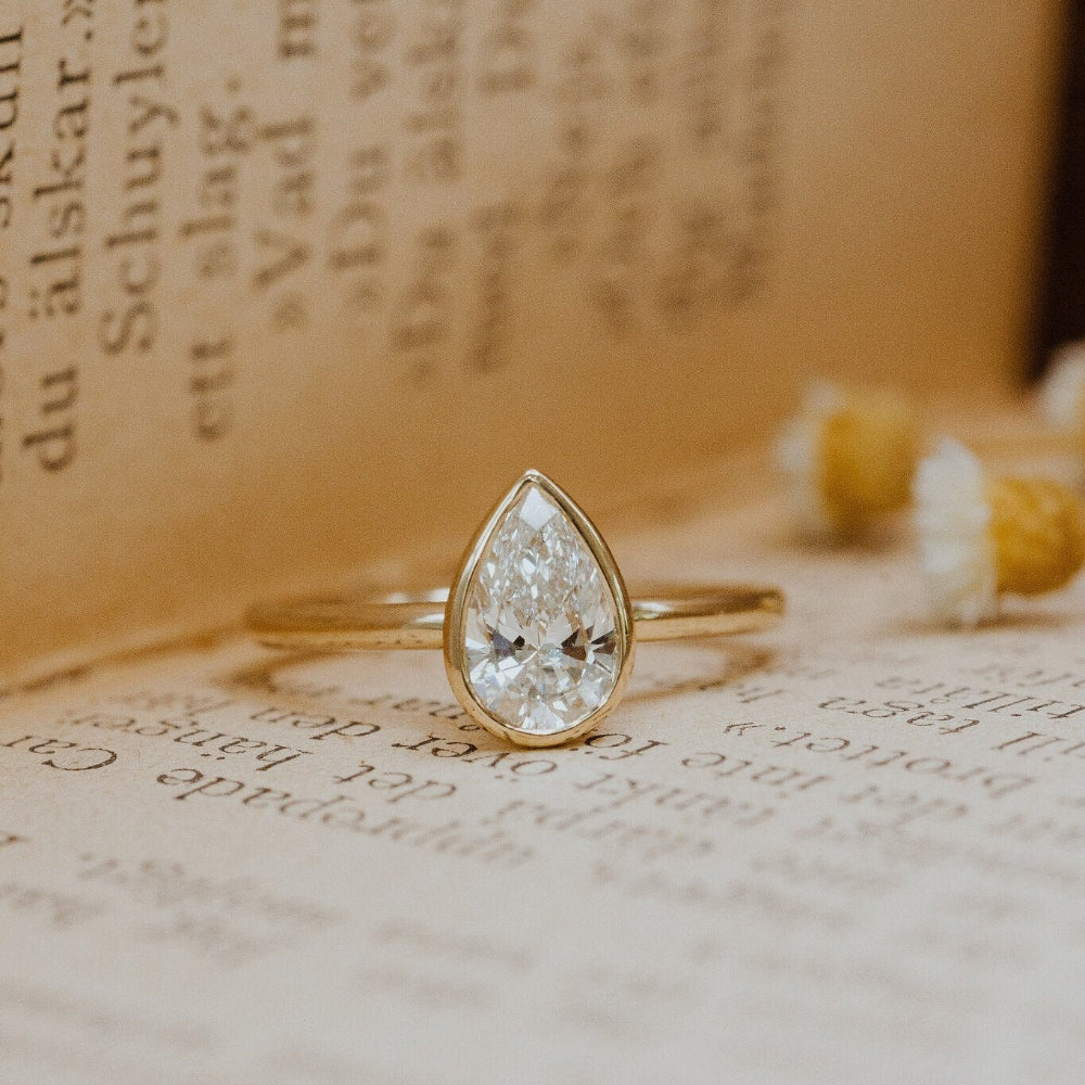 Gold Bailey ring with a pear-shaped diamond on an old book.