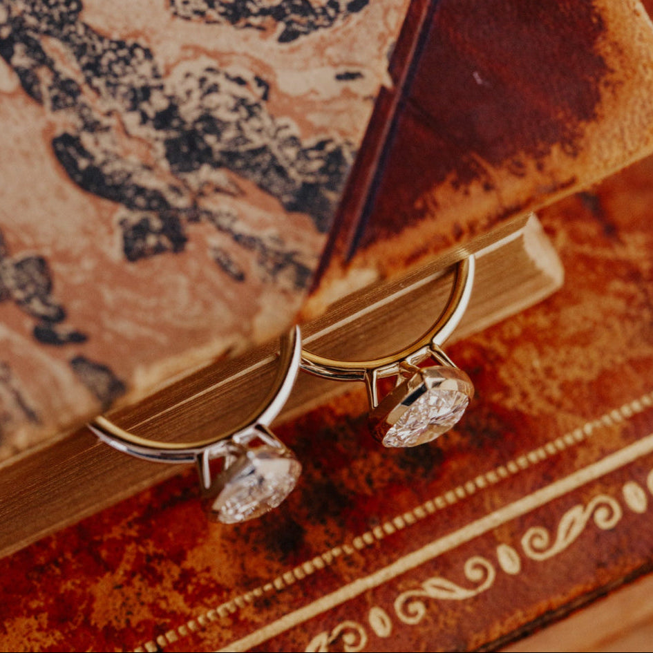 Two gold Bailey pear engagement rings on a decorative box.