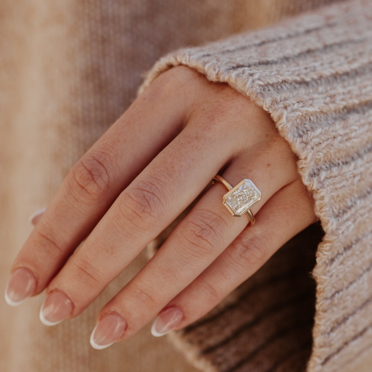 Close-up of a hand wearing the Bailey engagement ring with a radiant-cut diamond.