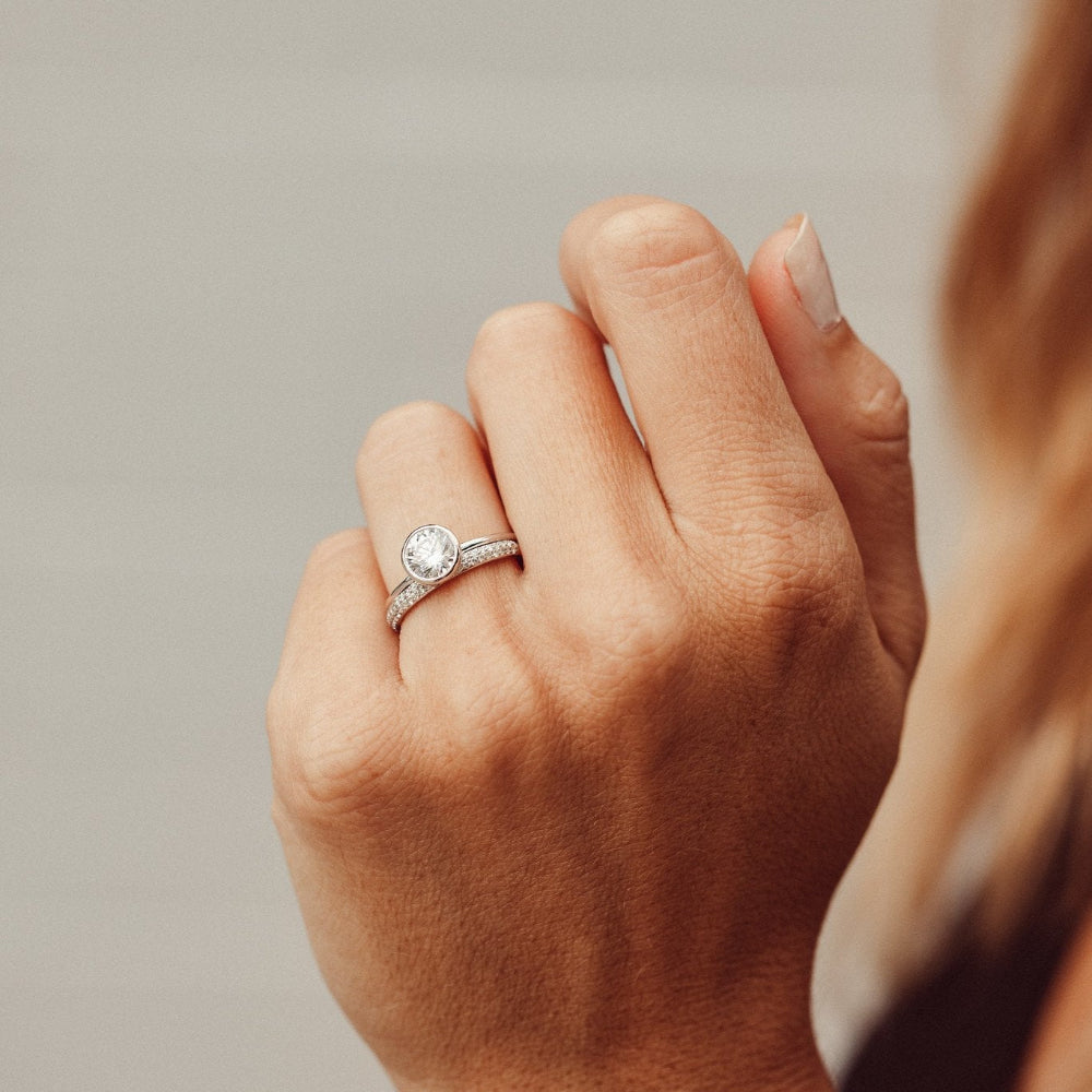 Hand wearing a Bailey round diamond ring  in white gold on a neutral background.