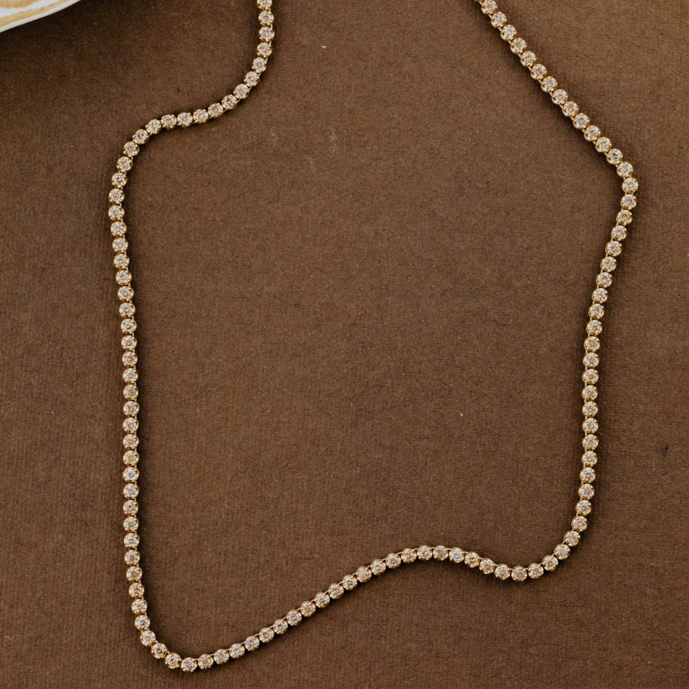 Champagne diamond tennis necklace on a brown background.