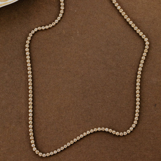 Champagne diamond tennis necklace on a brown background.