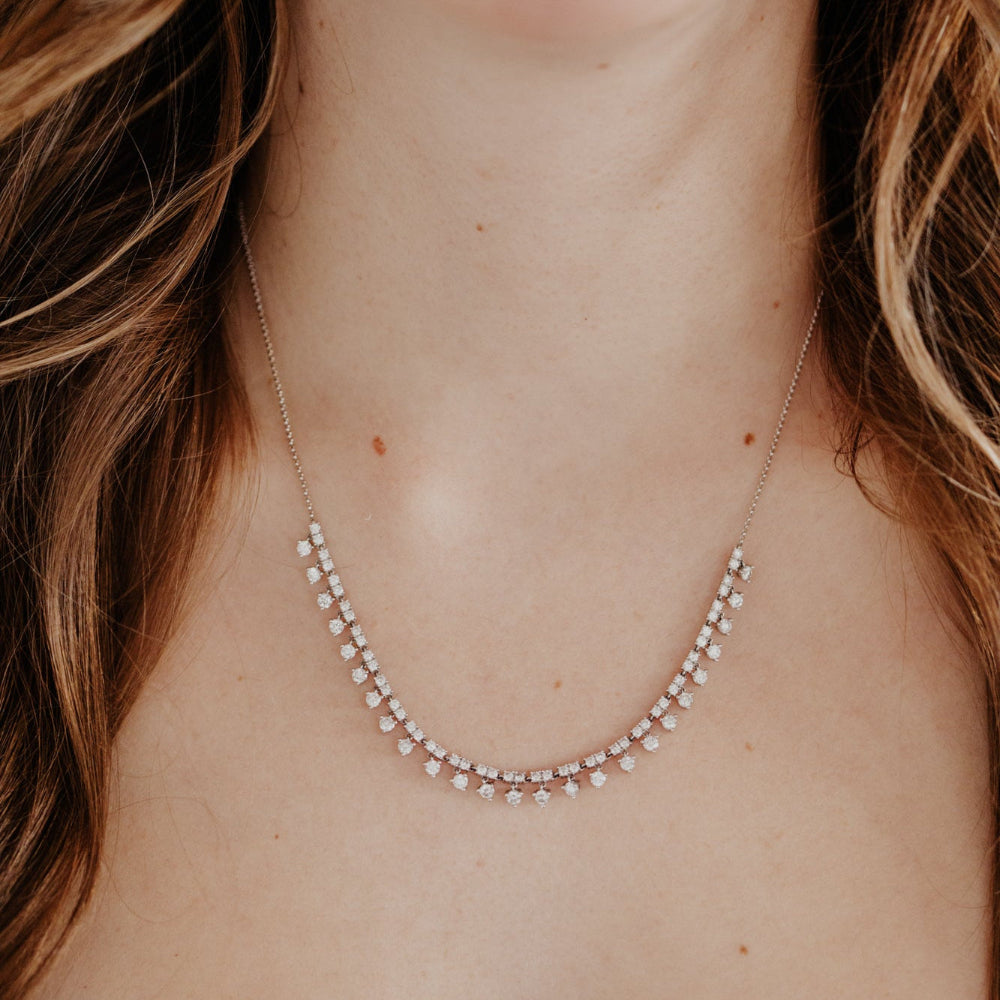 Close-up of a person wearing a delicate diamond necklace with a soft focus on the face and hair.