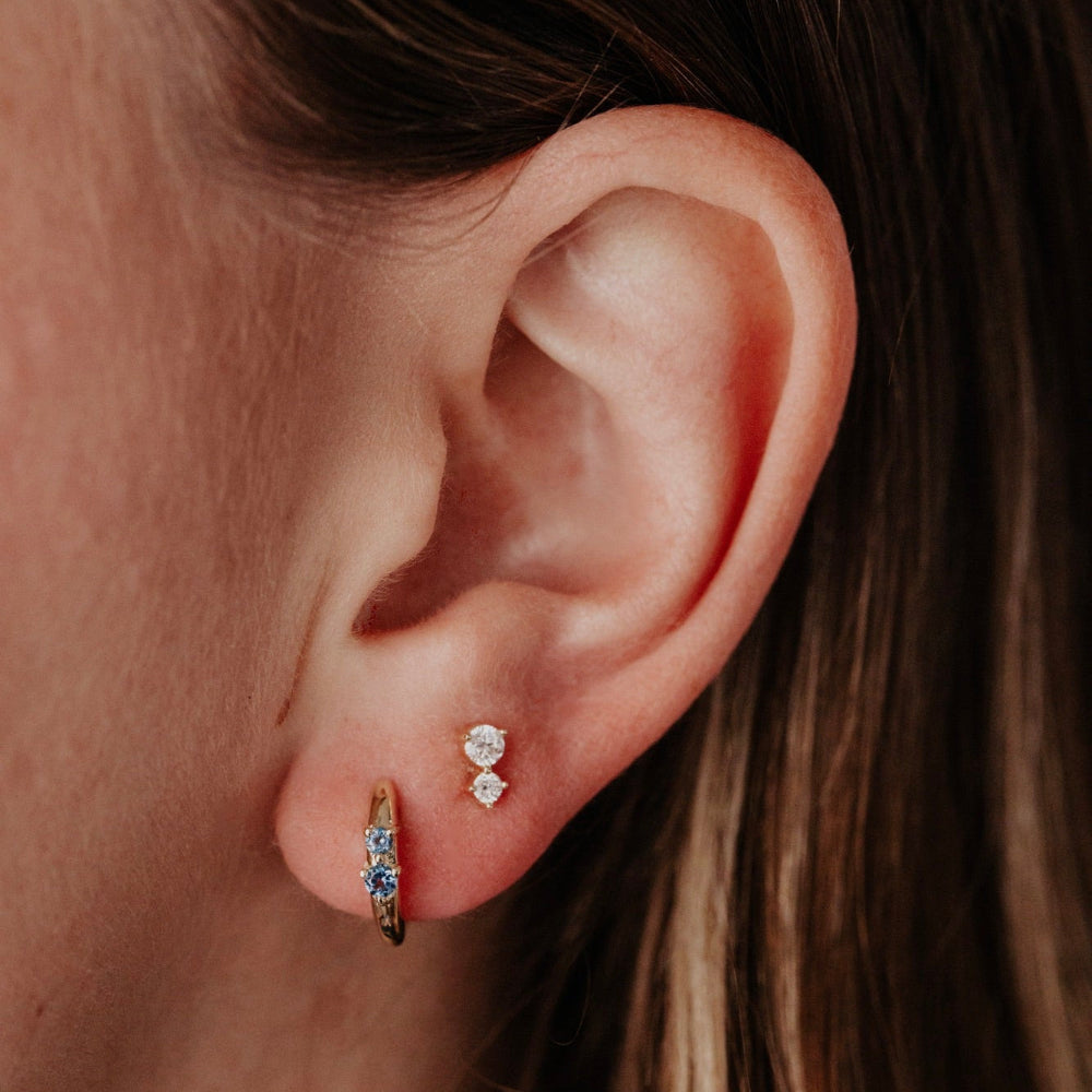 Close-up of an ear wearing gold blue topaz and diamond earrings