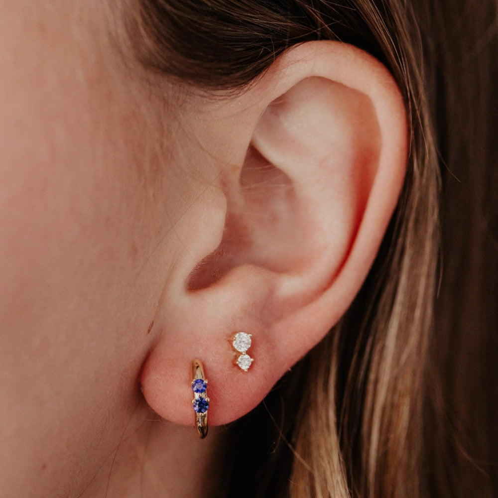 Close-up of an ear wearing two earrings with a blurred background