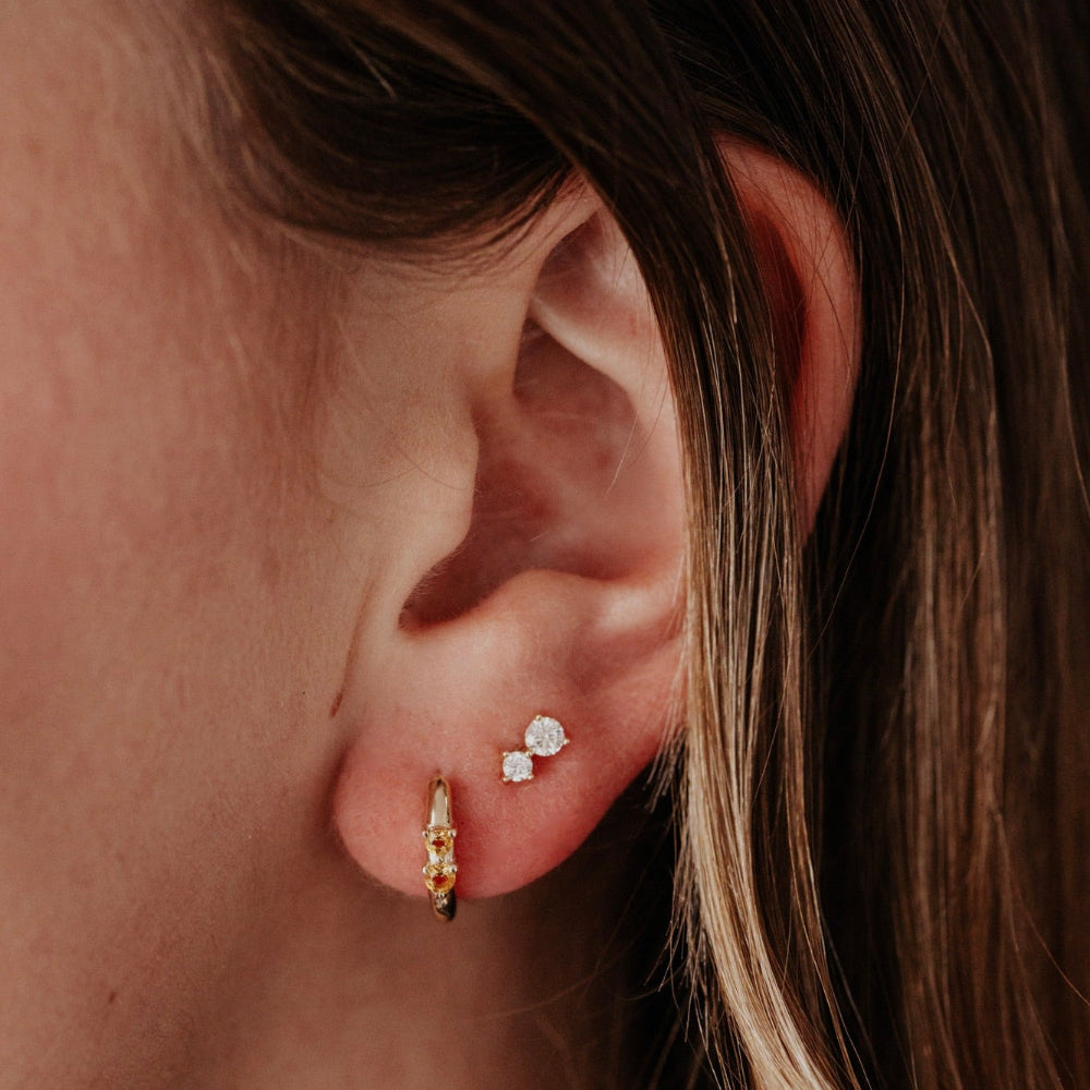 Close-up of an ear wearing gold earrings with a blurred background