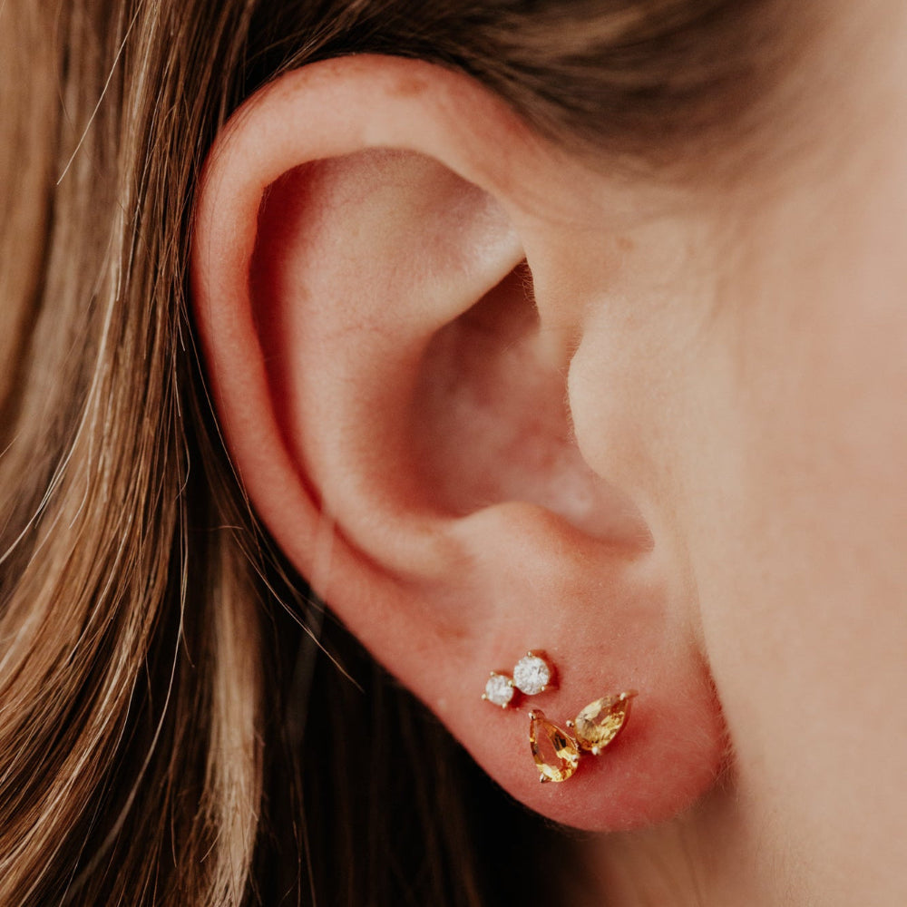Close-up of an ear with gold and diamond earrings.