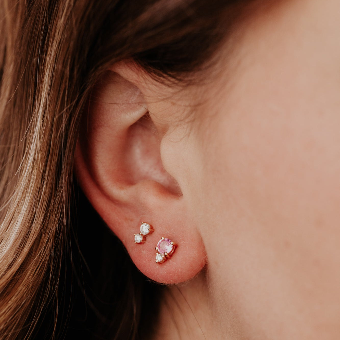 Close-up of an ear wearing two earrings with a blurred background