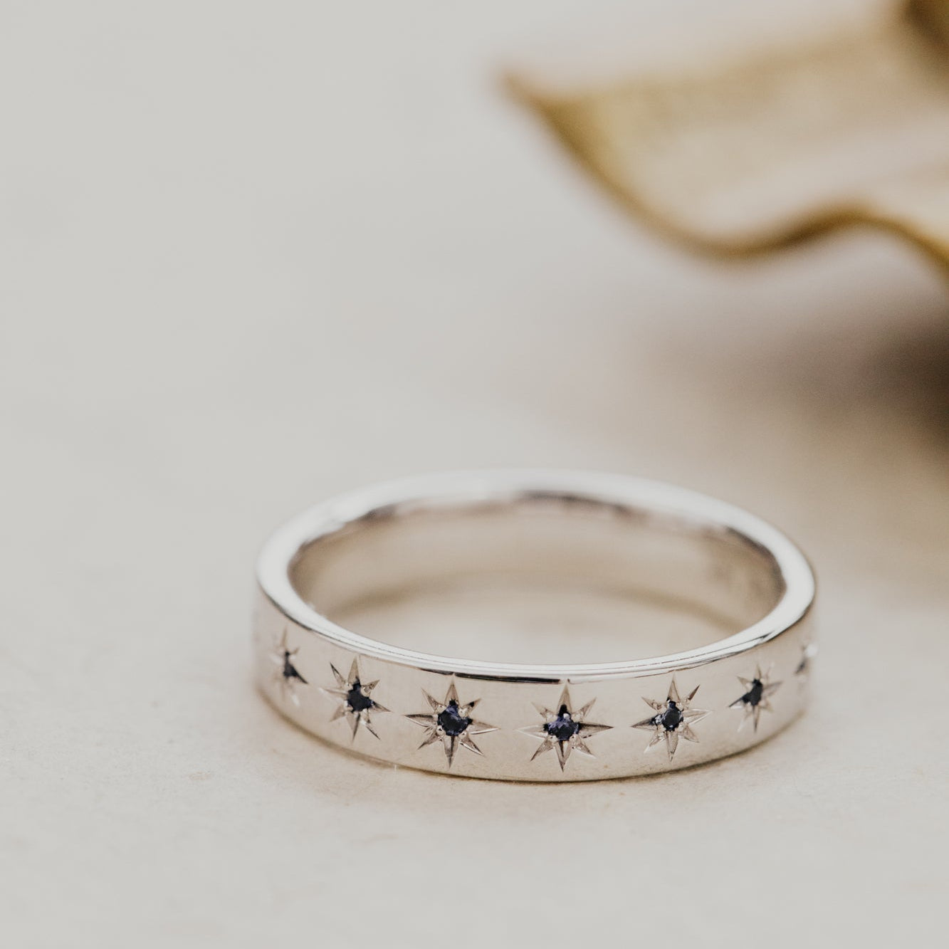 White gold Estelle band with blue sapphires set in a star-shaped cutouts on a light background.