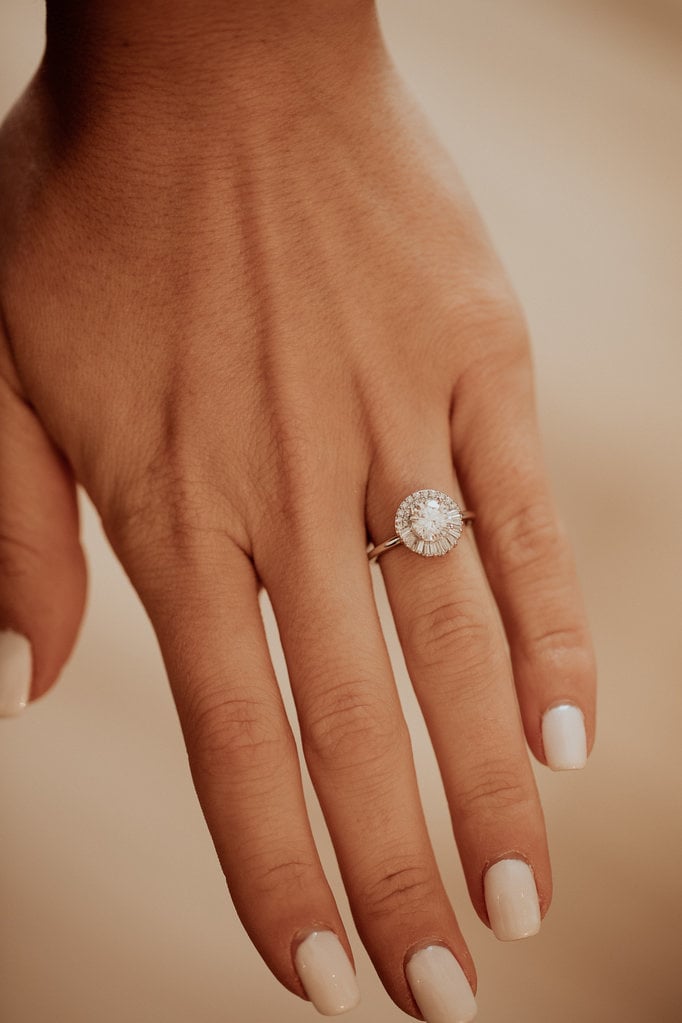 Close up of a hand wearing the round Florence engagement ring with diamond halo.