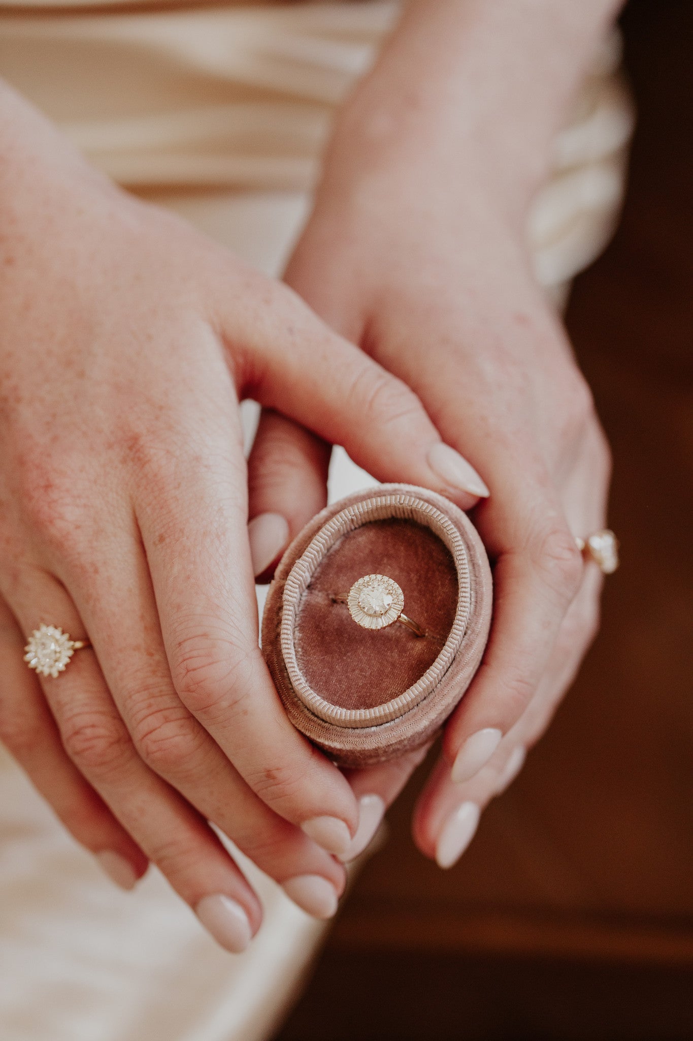 Close up of a person holding a pink velvet box with the Florence round diamond engagement ring.