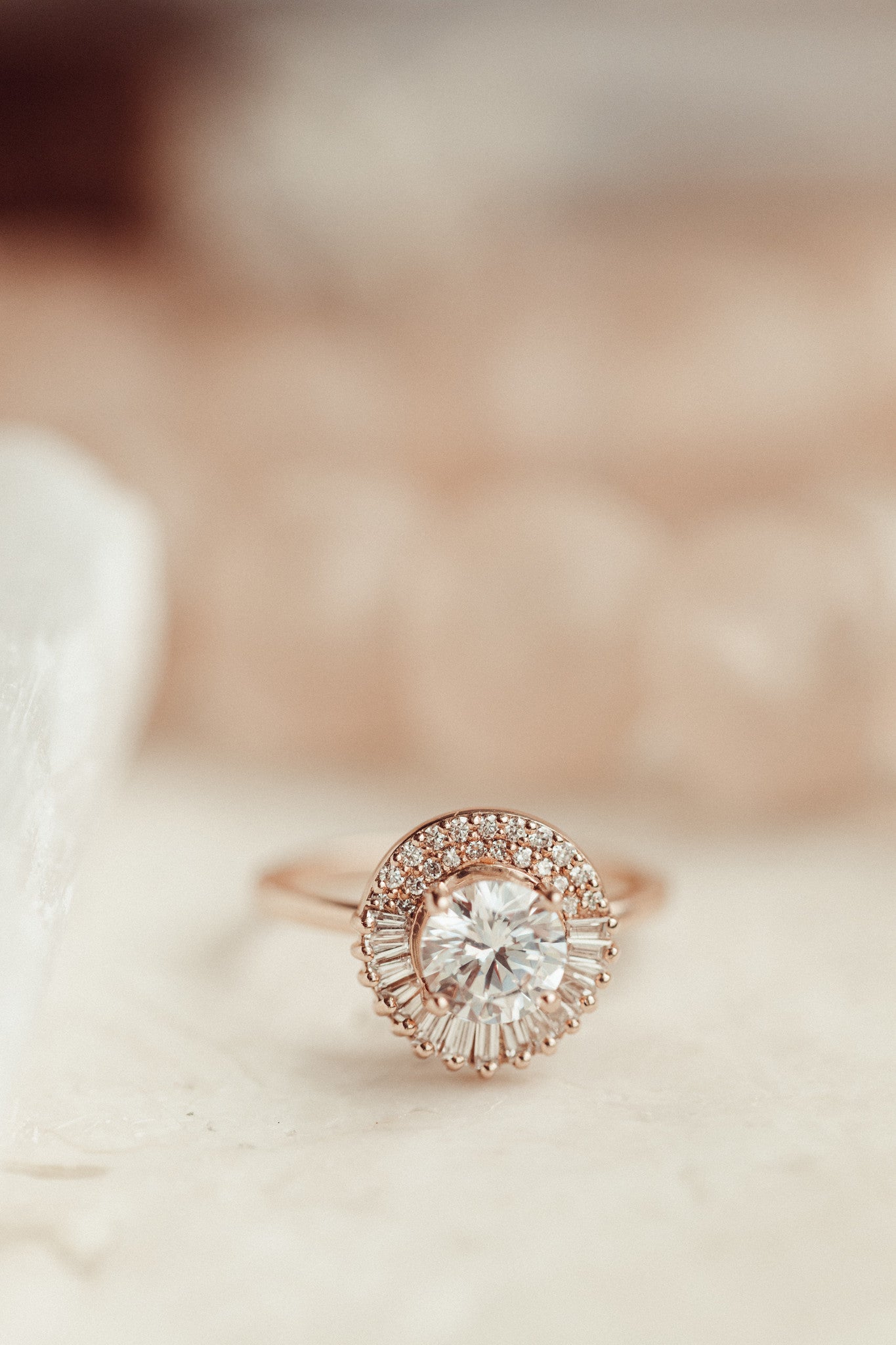 Close up of the Florence round diamond engagement ring with a diamond halo with a blurred background.