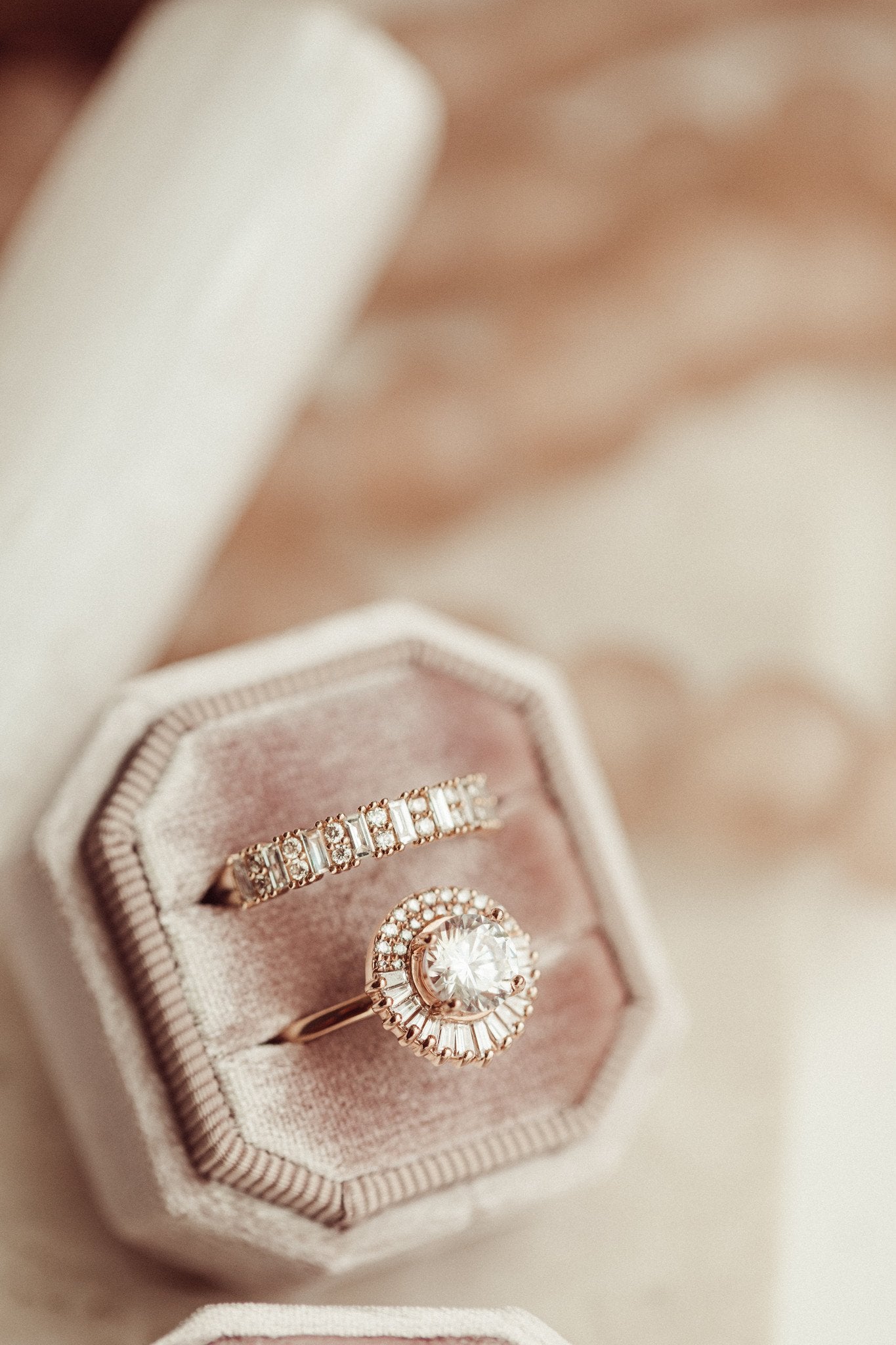 The Florence round diamond engagement ring and a diamond band in a pink velvet ring box with a blurred background.