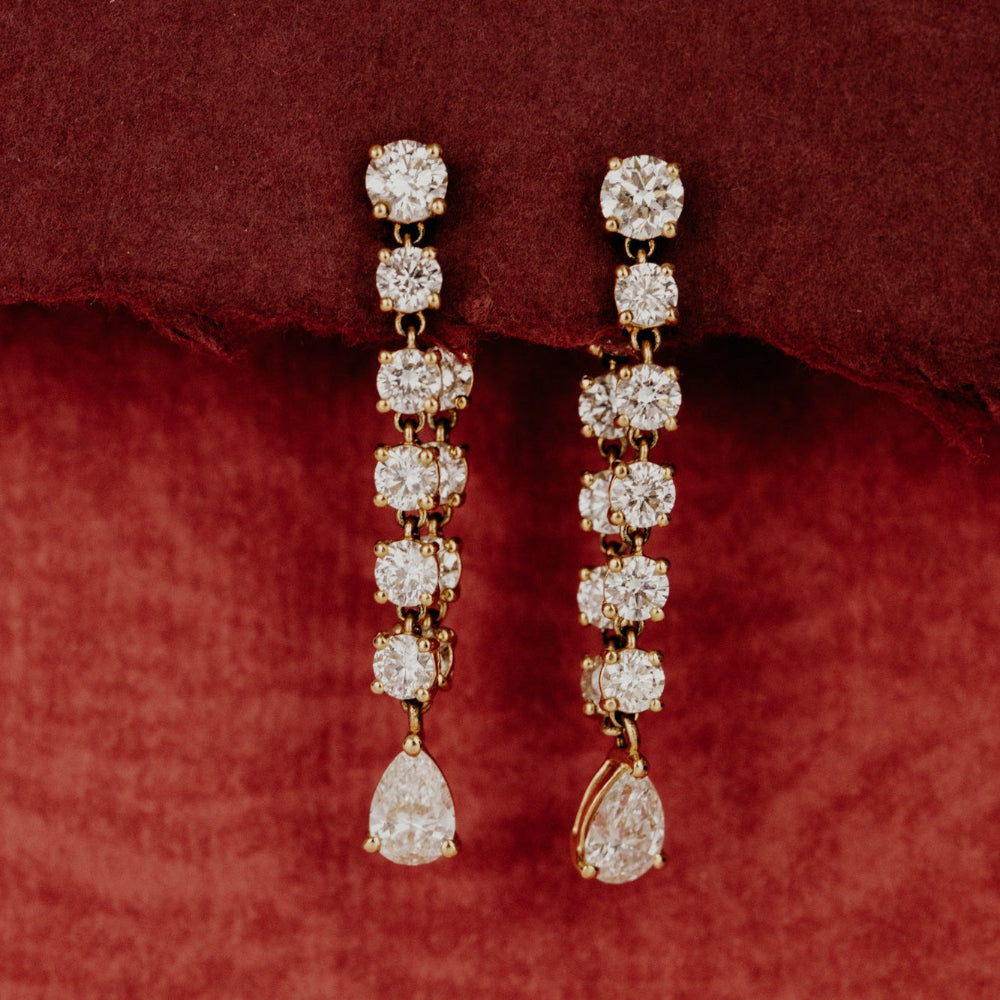 Pair of front to back diamond earrings on a red fabric background.