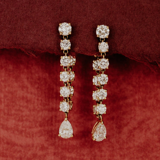 Pair of front to back diamond earrings on a red fabric background.