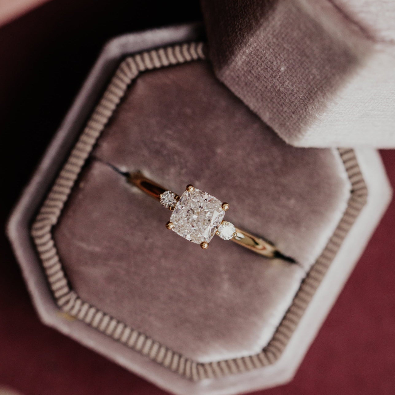 Gold Isla engagement ring with a cushion diamond on a brown velvet ring box.